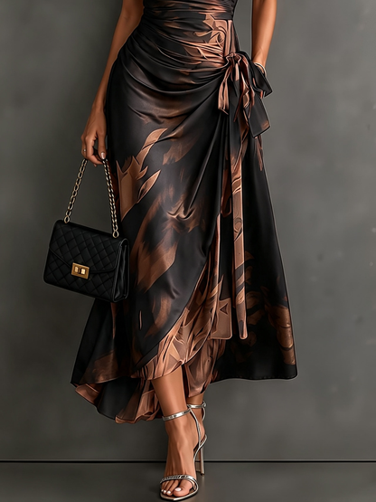 VESTIDO MIDI CRUZADO CON ESTAMPADO ABSTRACTO ROJO Y NEGRO, CUELLO CAMISERO CON ESCOTE EN V, MANGA CORTA, CINTURA ANUDADA Y BAJO ASIMÉTRICO CON VOLANTE